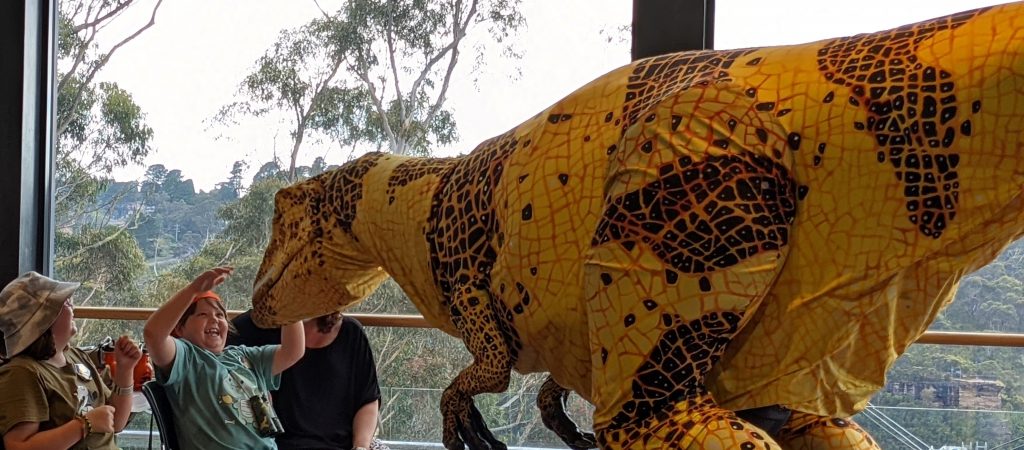 excited child meeting a dinosaur at raptor tales scenic world