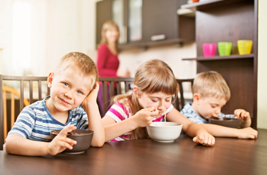 three children eating soup happily