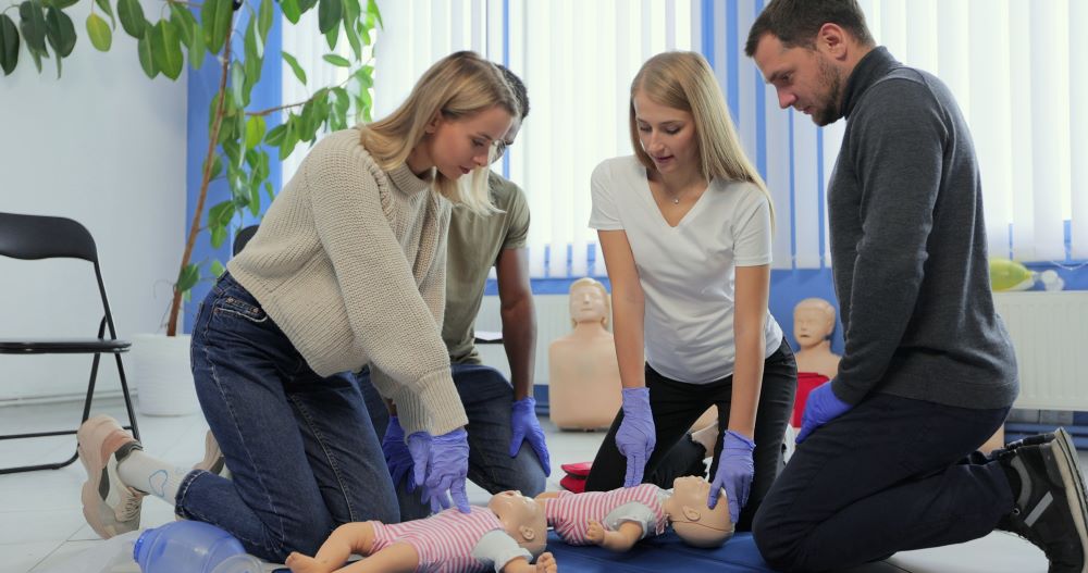 life first aid courses blue mountains - a group of people are learning CPR on a dummy