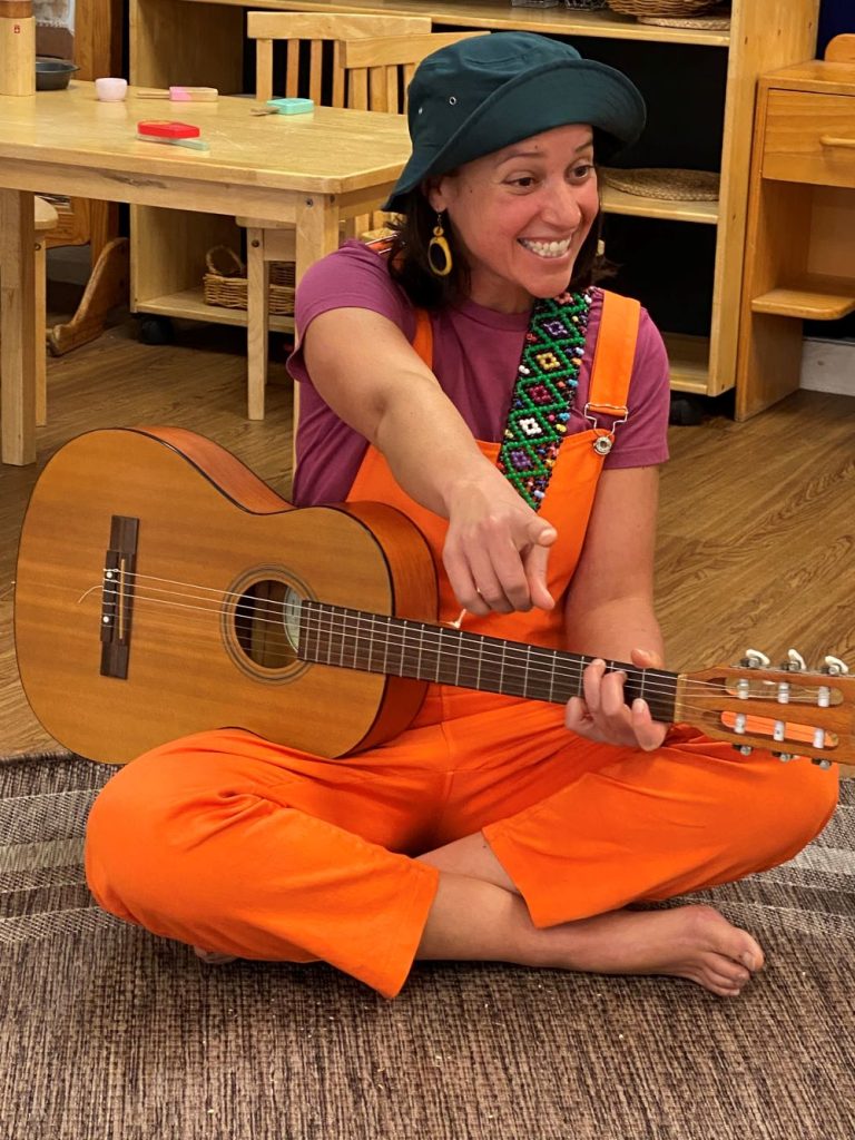 nikki noodle music classes katoomba nikki is smiling and pointing while holding her guitar