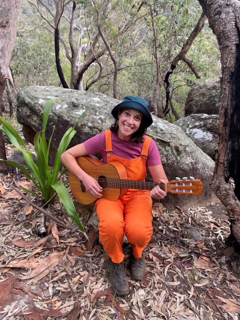 nikki noodle music classes katoomba nikki is sitting on a rock with her guitar